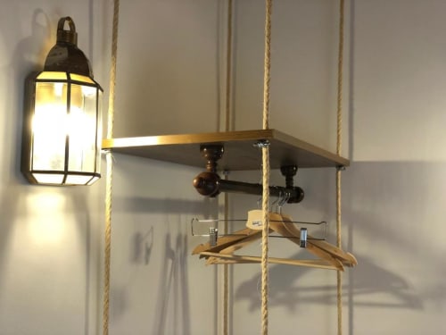 Rope-hung wooden shelf with black metal fixture and illuminated wall lantern in Almagro hotel room