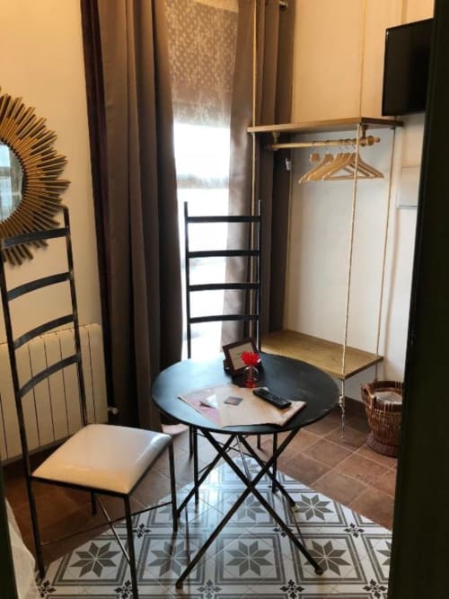 Modern studio in Almagro with round black table, chair, clothing rack, and city views through draped windows