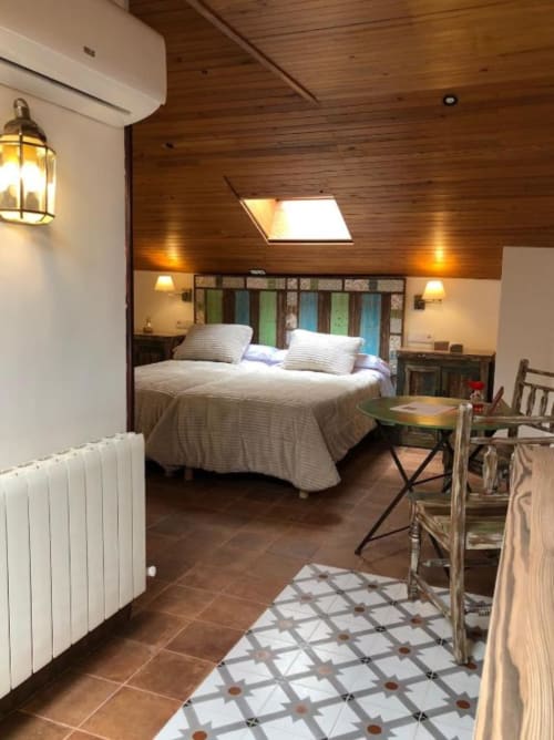 Spacious romantic bedroom at Retiro del Teatro with wooden ceiling, queen bed, skylight, and rustic décor in Almagro