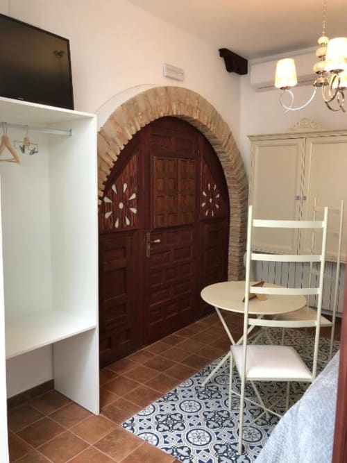 Cozy Room 7 at Complejo Turístico Retiro del Teatro with arched wooden door, white chairs, and tile flooring in Almagro,