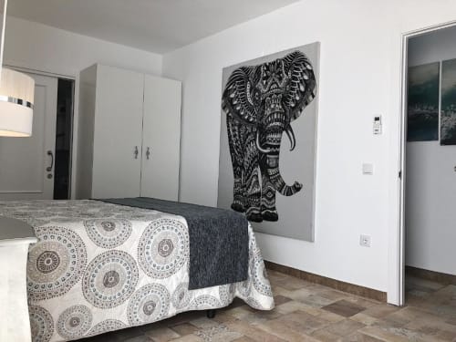 Modern bedroom in Almagro with decorative elephant wall art, patterned bedspread, white wardrobe, and tile flooring.
