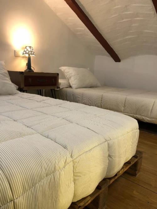 Cozy attic bedroom with two beds, bedside lamp, and exposed wooden beams at Complejo Turístico Retiro del Teatro