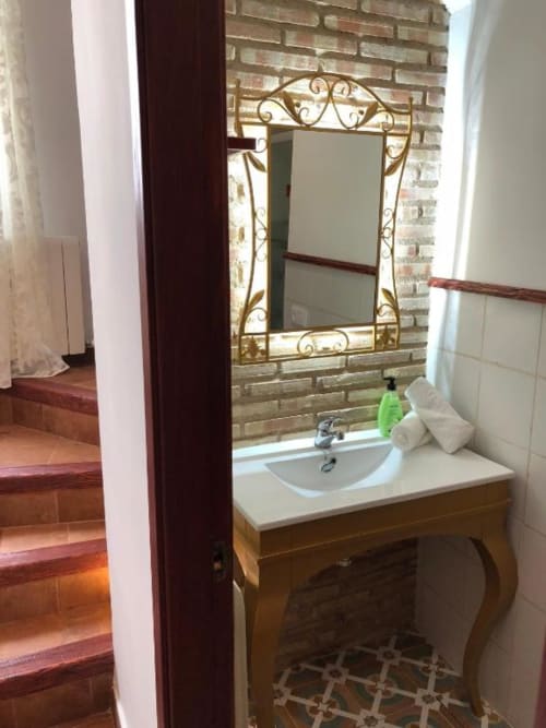 Elegant bathroom sink with ornate gold-framed mirror and brick wall at Complejo Turístico Retiro del Teatro in Almagro,