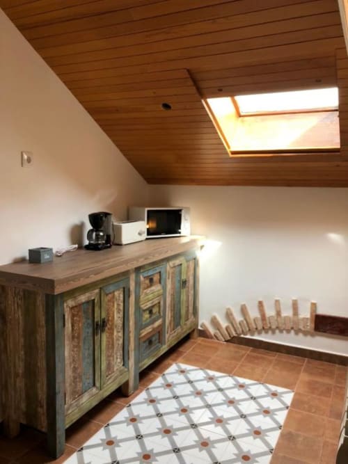 Attic bedroom with skylight, rustic green cabinet, coffee maker, and geometric tile floor at Retiro del Teatro, Almagro