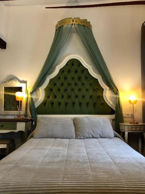 Luxurious bedroom with green tufted headboard and draped canopy at Retiro del Teatro, Almagro
