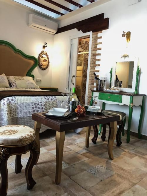 Suite B at Retiro del Teatro with green headboard bed, dark wood furniture, and brick accent wall in Almagro