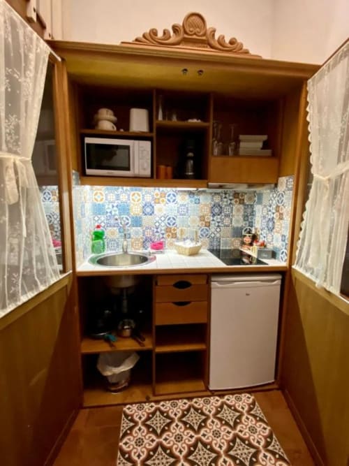 Charming dollhouse-style kitchenette with wooden cabinets, tiled backsplash, sink, microwave, and refrigerator at Complejo