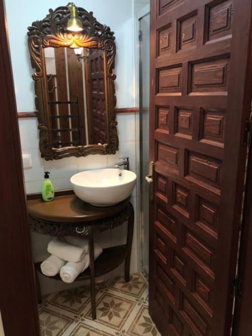 Elegant bathroom in Room 5 at Retiro del Teatro with ornate mirror, round vessel sink, dark wood vanity, and decorative