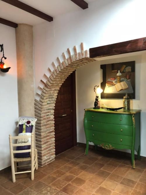 Rustic entryway at Retiro del Teatro with brick archway, green dresser, wooden beams, and traditional Spanish décor