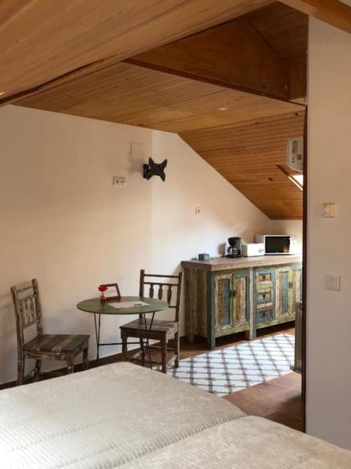 Loft-style room at Retiro del Teatro with wooden beams, vintage furniture, green table, and rustic cabinet in Almagro