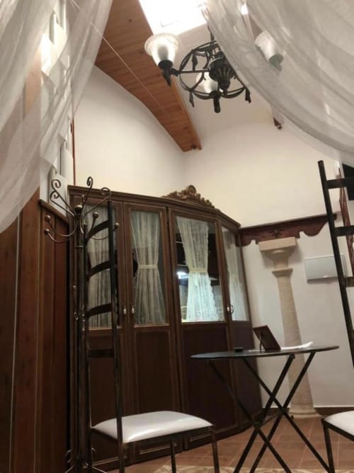 Elegant bedroom with wooden wardrobe, sheer curtains, and exposed beam ceiling at Retiro del Teatro boutique hotel, Almagro