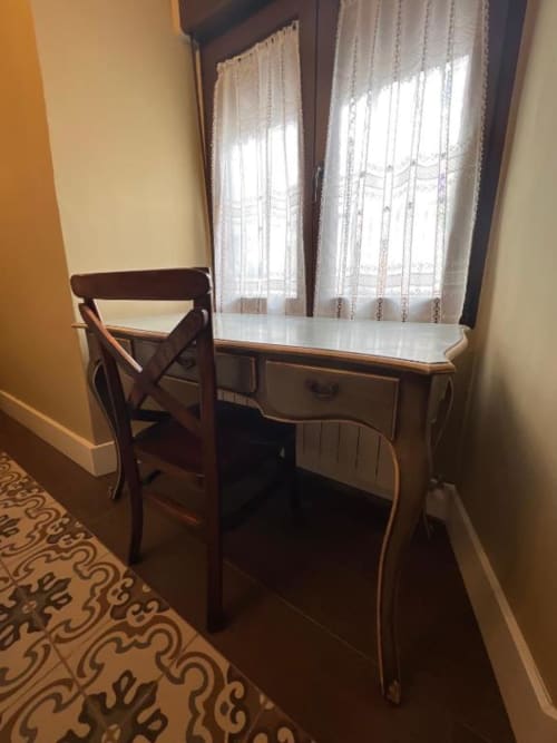 Elegante escritorio con silla de madera junto a las ventanas en la Suite Deluxe del Retiro del Teatro, Almagro