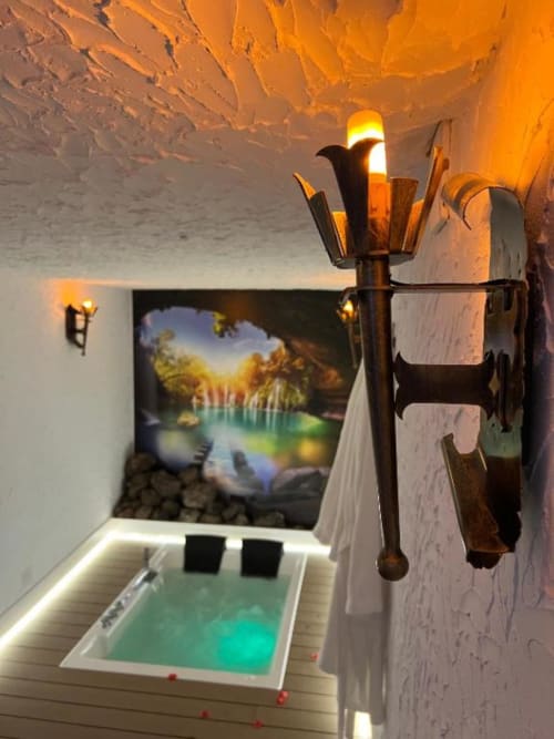 Romantic cave suite with illuminated jacuzzi, decorative torches, and landscape artwork at Complejo Turístico Retiro del