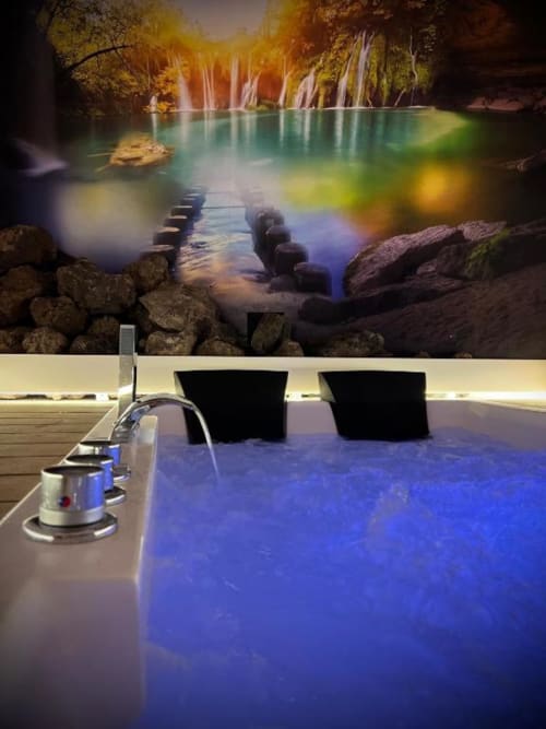 Luxury Jacuzzi suite at Retiro del Teatro with waterfall view, blue illuminated hot tub, and romantic cave setting in