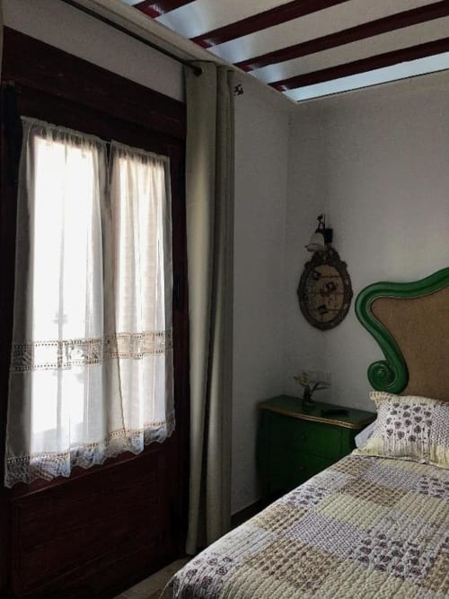Suite B bedroom at Retiro del Teatro with green headboard, beamed ceiling, and landmark views from Almagro, Ciudad Real