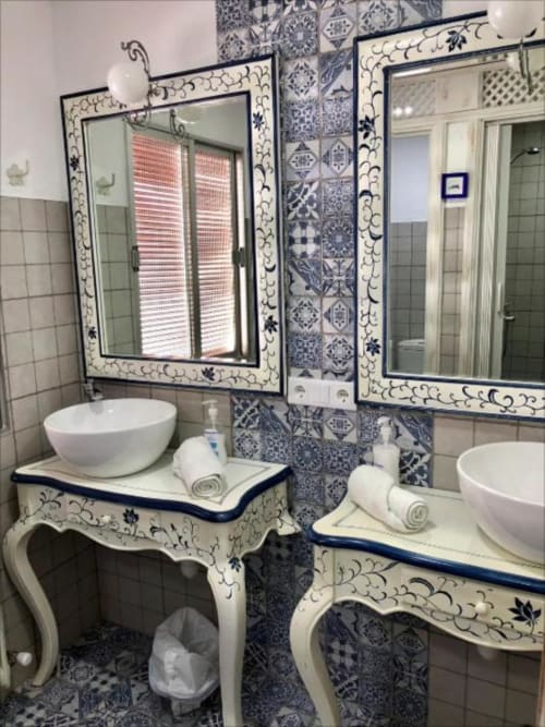 Blue and white ceramic bathroom with dual vessel sinks, ornate mirrors, and decorative tilework in Corral de Comedias Studio