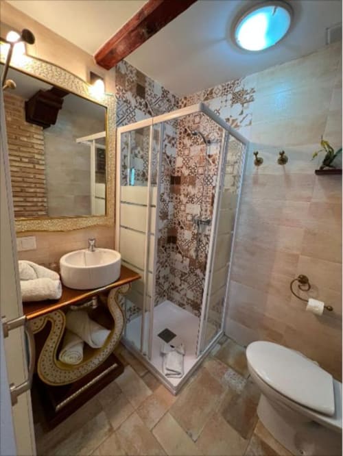 Modern bathroom at Complejo Turístico Retiro del Teatro with walk-in shower, round sink, toilet, and patterned tile accents