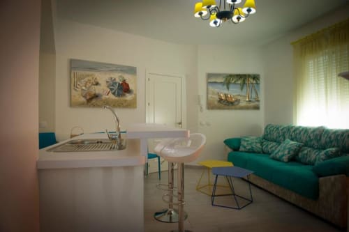 Sala de estar de apartamento de lujo con cocina, sofá turquesa, mesa de comedor y arte temático de playa en Complejo Turístico Retiro