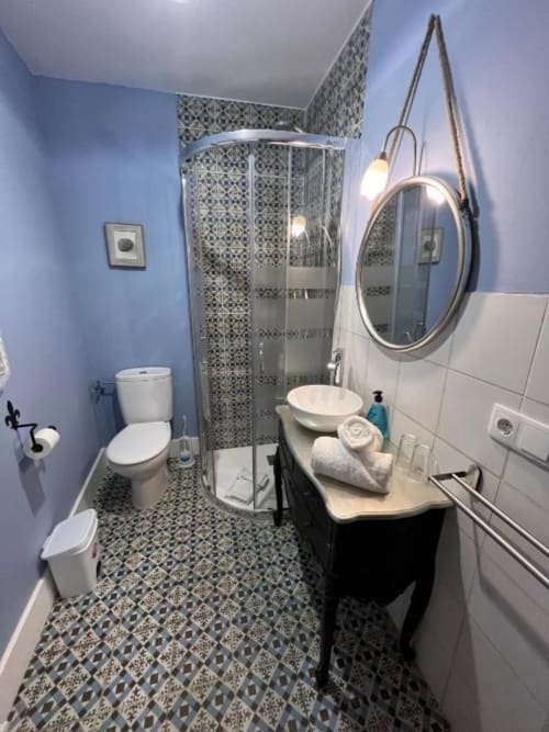 Modern bathroom at Complejo Turístico Retiro del Teatro with blue walls, patterned tile flooring, walk-in shower, and vanity
