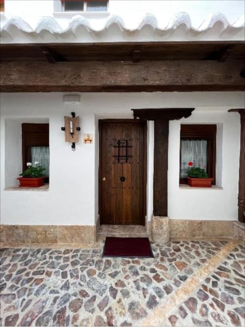 Traditional whitewashed facade of Complejo Turístico Retiro del Teatro in Almagro with wooden door, potted plants, and stone