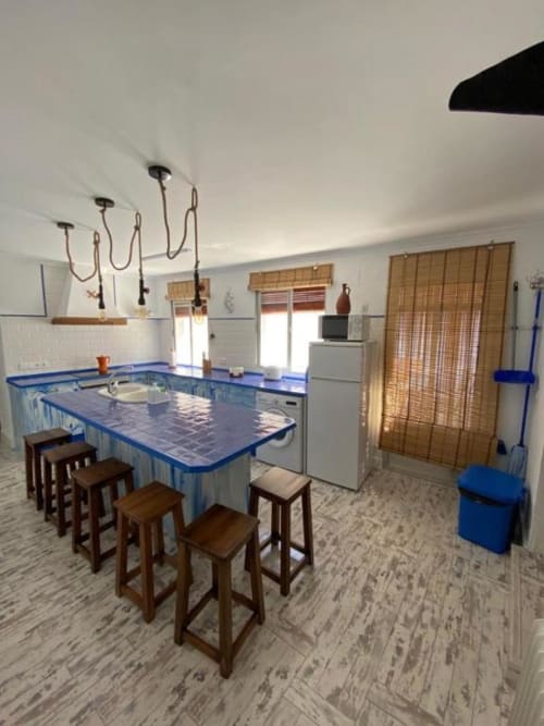 Cocina moderna con isla de azulejos azules y taburetes de madera en Villa Corral de Comedias, Almagro