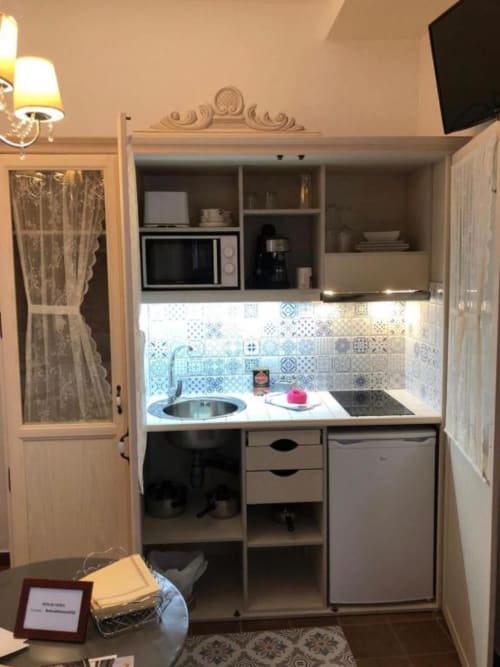 Compact kitchenette with sink, stovetop, refrigerator, microwave, and decorative blue tile backsplash in Room 2 at Retiro del