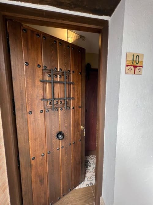 Puerta de entrada de madera ornamentada con herrajes decorativos y placa del número 10 en Complejo Turístico Retiro del Teatro