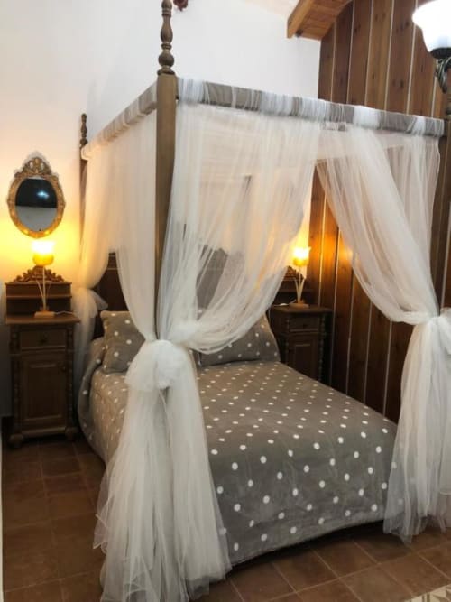 Elegant four-poster canopy bed with sheer white drapes and polka dot bedding at Complejo Turístico Retiro del Teatro, Almagro