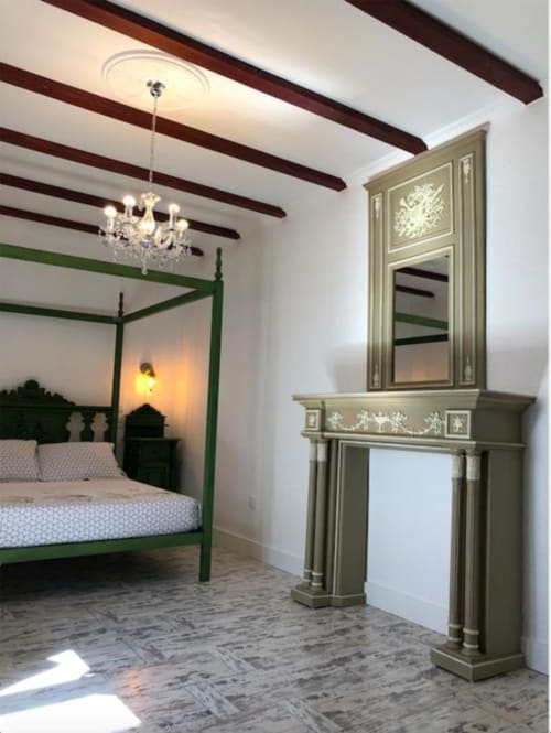 Elegant bedroom with green four-poster bed, crystal chandelier, dark wooden beams, and ornate mirror in Corral de Comedias