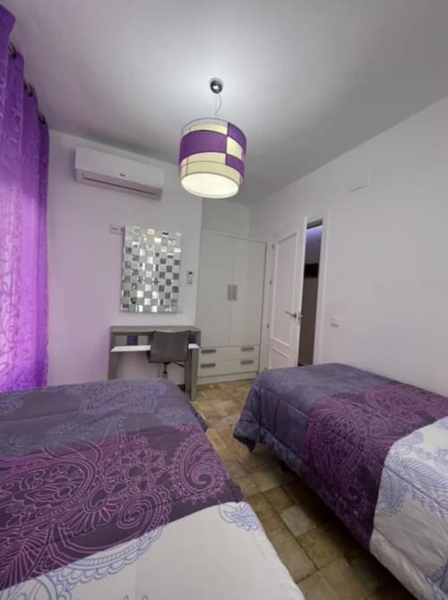Purple-themed twin bedroom in Deluxe Apartment A at Complejo Turístico Retiro del Teatro, Almagro with modern pendant light