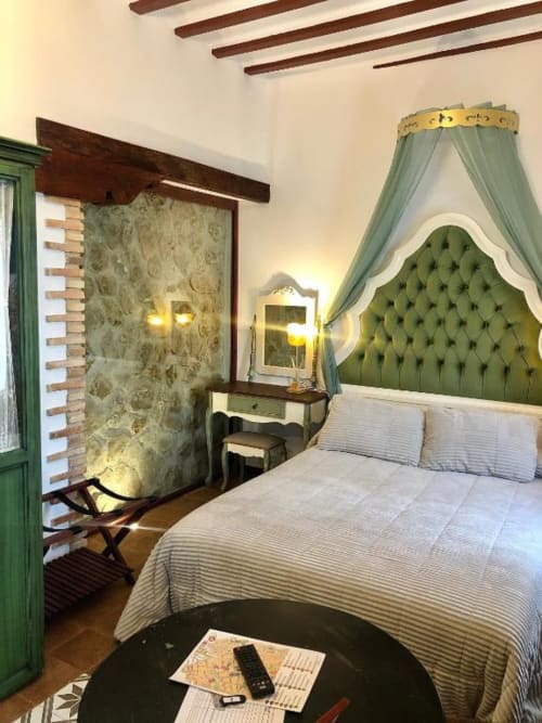 Dormitorio elegante con cabecera capitonada verde, dosel, chimenea y vistas a la ciudad en Retiro del Teatro, Almagro