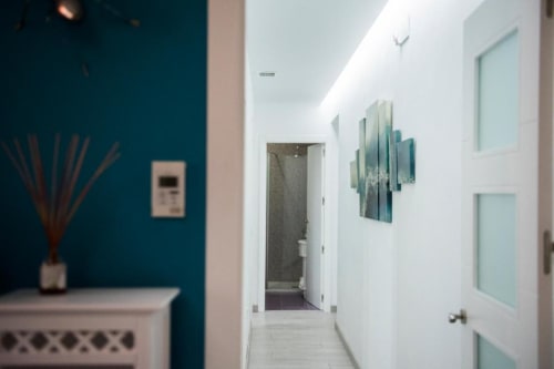 Pasillo moderno en Apartamento de Lujo en Retiro del Teatro, Almagro, con pared de acento en verde azulado, puertas blancas y diseño contemporáneo