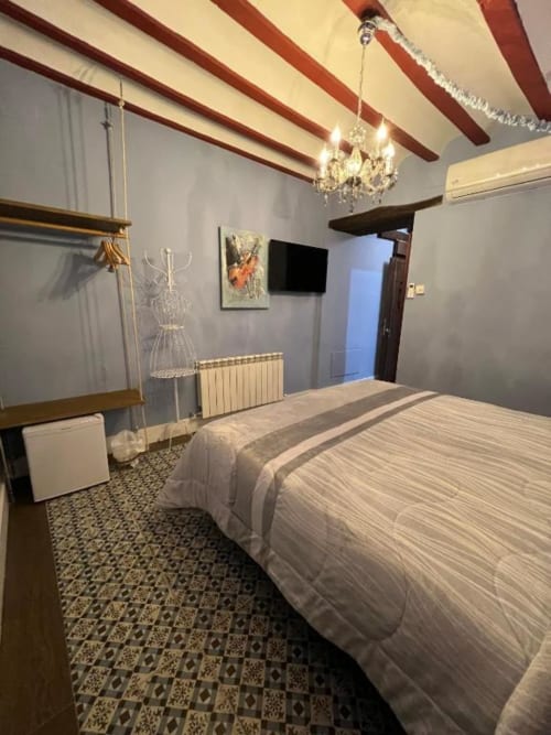 Elegant double bedroom at Complejo Turístico Retiro del Teatro with exposed beams, crystal chandelier, and inner courtyard