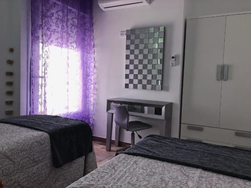Deluxe apartment bedroom at Complejo Turístico Retiro del Teatro, Almagro with twin beds, desk, and purple curtains.