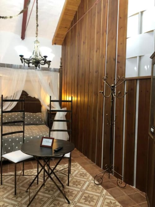 Elegant hotel room at Retiro del Teatro with wooden walls, canopy bed, round table, and decorative fireplace in Almagro,