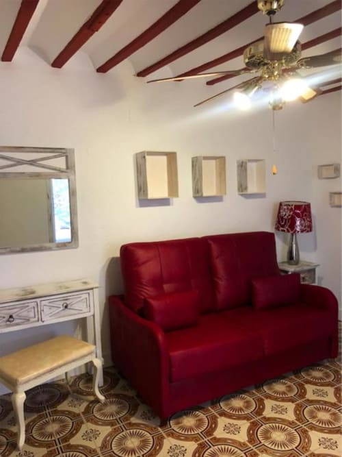Elegante sala de estar con sofá rojo, vigas de madera vista y mobiliario decorativo en Complejo Turístico Retiro