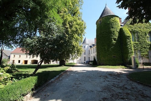Historic château courtyard with ivy-covered towers and lush grounds at La Ferme du Châtaignier, Boissy-le-Sec
