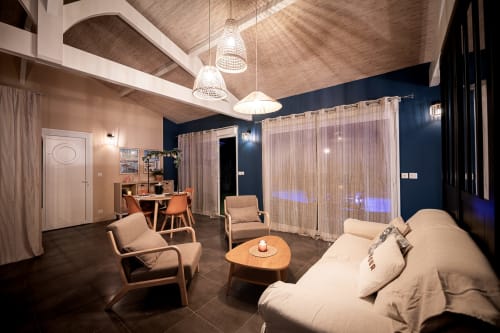 Modern living room at Villa Eden Bleu with beige seating, pendant lights, and blue accent wall in Biscarrosse