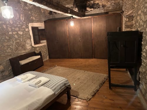 Habitación MUSSOL en Casa Tapiolas B&B en Molló, Girona, con cama de madera, armario y paredes de piedra