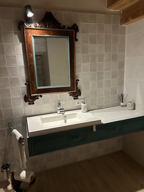 Baño elegante en Casa Tapiolas con doble lavabo, espejo de madera ornamentado y azulejos blancos en Molló