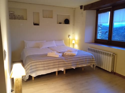 Dormitorio luminoso en Casa Tapiolas en Molló con cama queen, iluminación cálida y vistas a las montañas