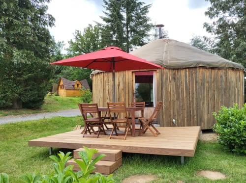 Wooden yurt cottage with red umbrella and wooden deck seating at Les Refuges Du Chalet, Jalhay