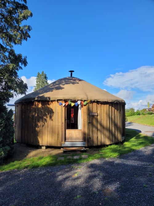 Wooden yurt accommodation with tan canvas roof at Les Refuges Du Chalet in Jalhay, Belgium, set in green garden surroundings