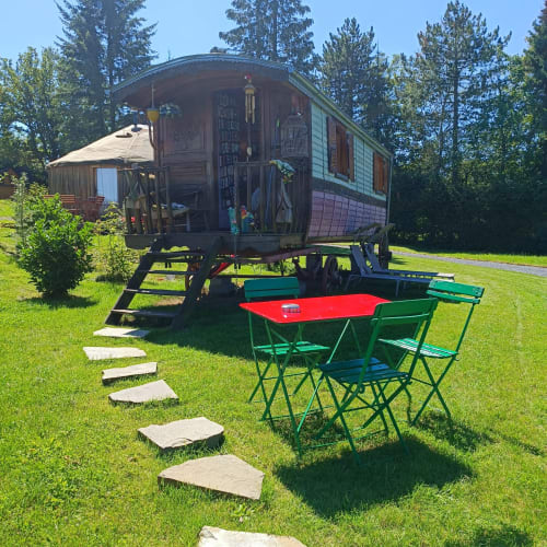 La Roulotte des Oiseaux, caravane vintage avec table rouge et chaises vertes dans le jardin des Refuges Du Chalet, Jalhay