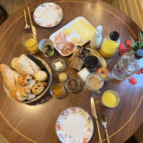 Breakfast spread at Les Refuges Du Chalet with pastries, cheese, meats, jams, and juice on wood table, Jalhay