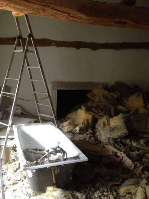Renovation work at Domaine de l'Ocrerie showing interior demolition with ladder and debris in Pourrain