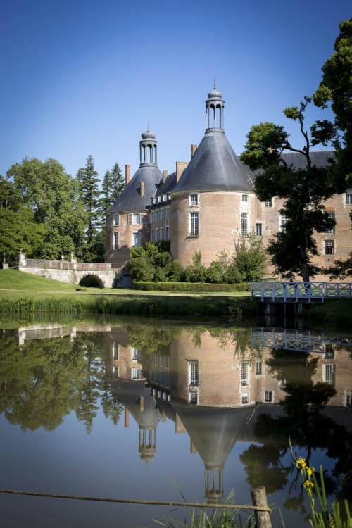 Domaine de l'Ocrerie château reflected in water with manicured grounds in Pourrain, France