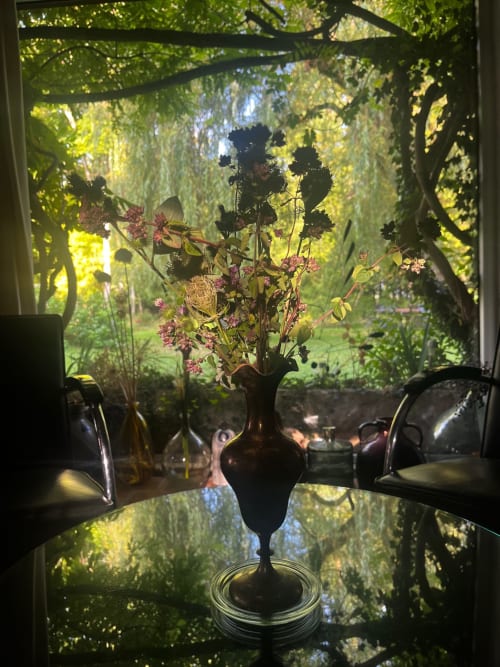 Vase sombre avec fleurs roses sur table en verre donnant sur le jardin du Domaine de l'Ocrerie, Pourrain