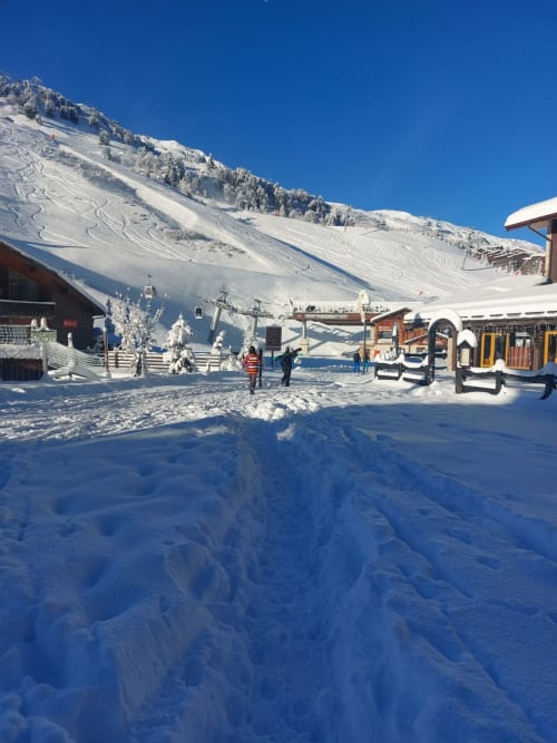Base de la station de ski enneigée de CMD Méribel Le Pralin, Les Allues avec pentes de montagne et bâtiments alpins