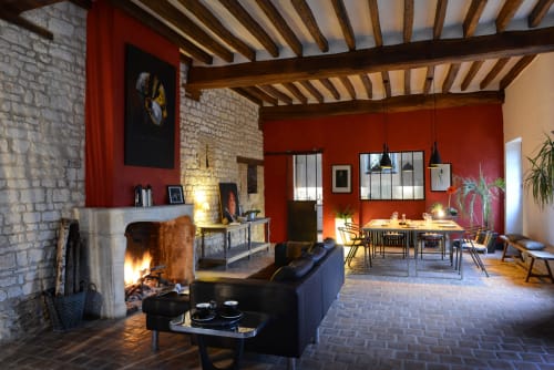 Élégant espace ouvert avec cheminée, plafond à poutres, murs rouges et coin repas au Domaine de l'Ocrerie